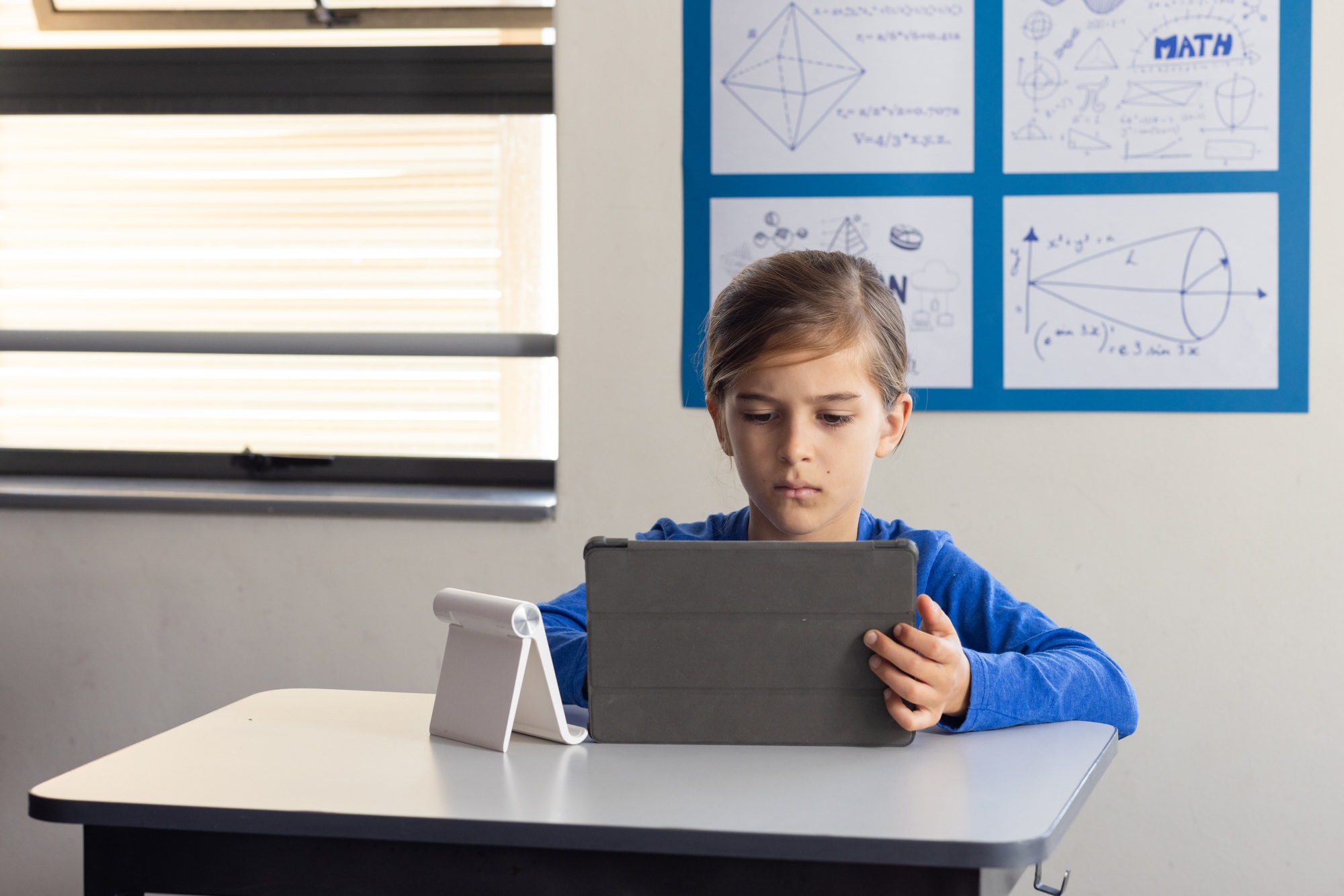 In school, boy using tablet for studying math in classroom