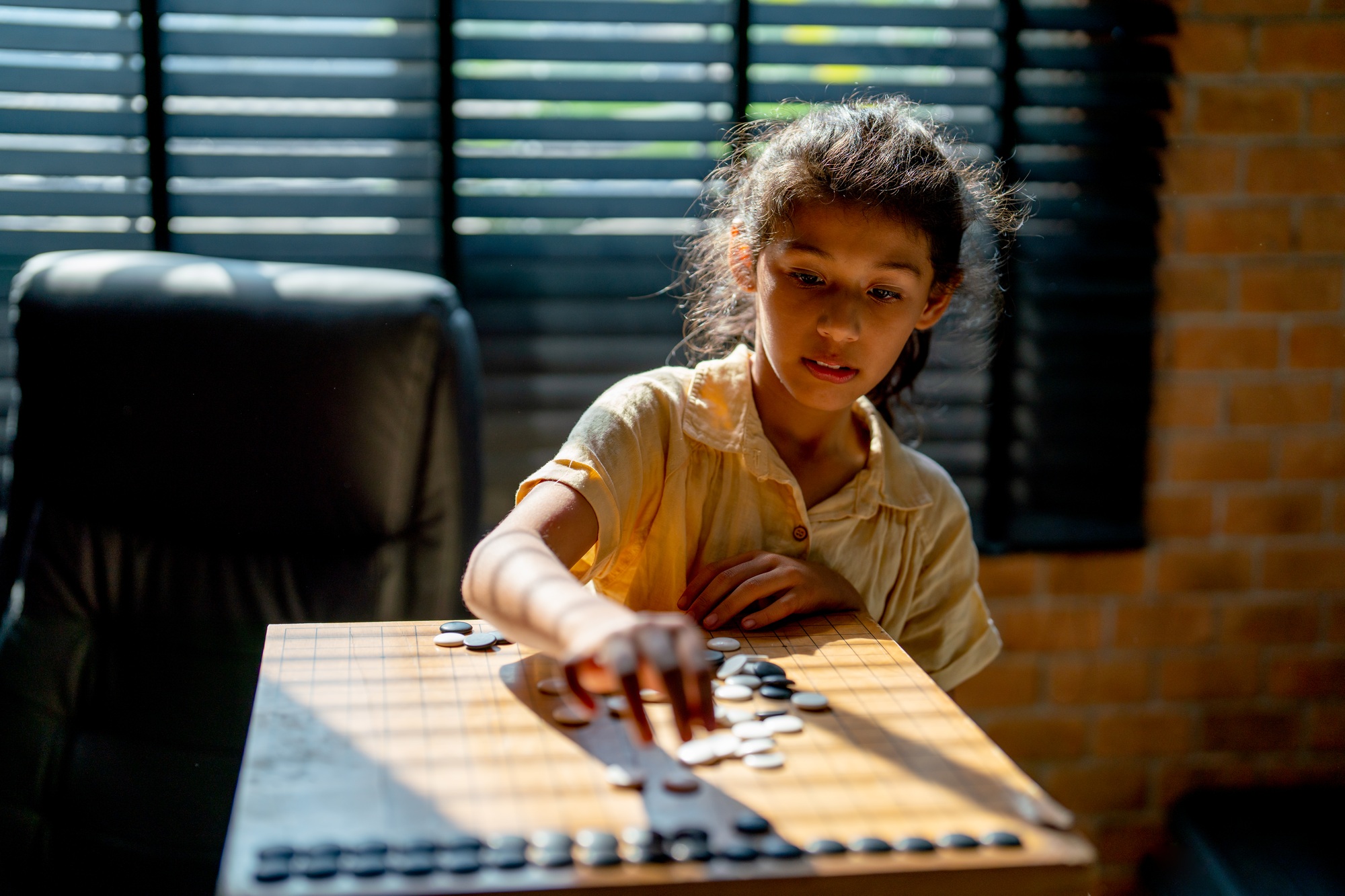 Little Asian girl concentrate and practice to play board game call Go in father working room