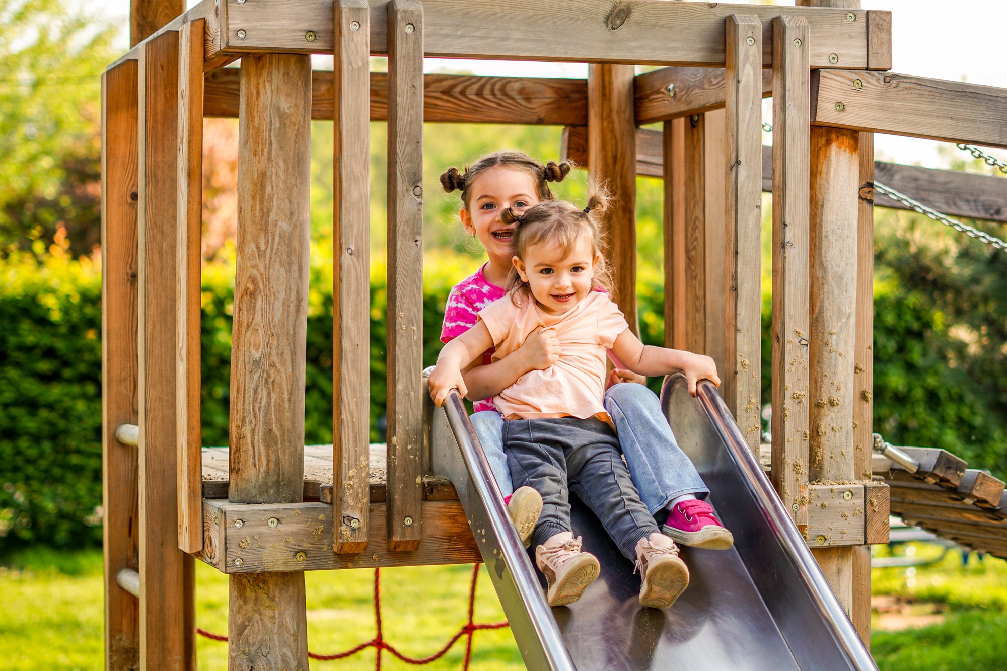 Sisters slide together in a playground - Children have fun togethe