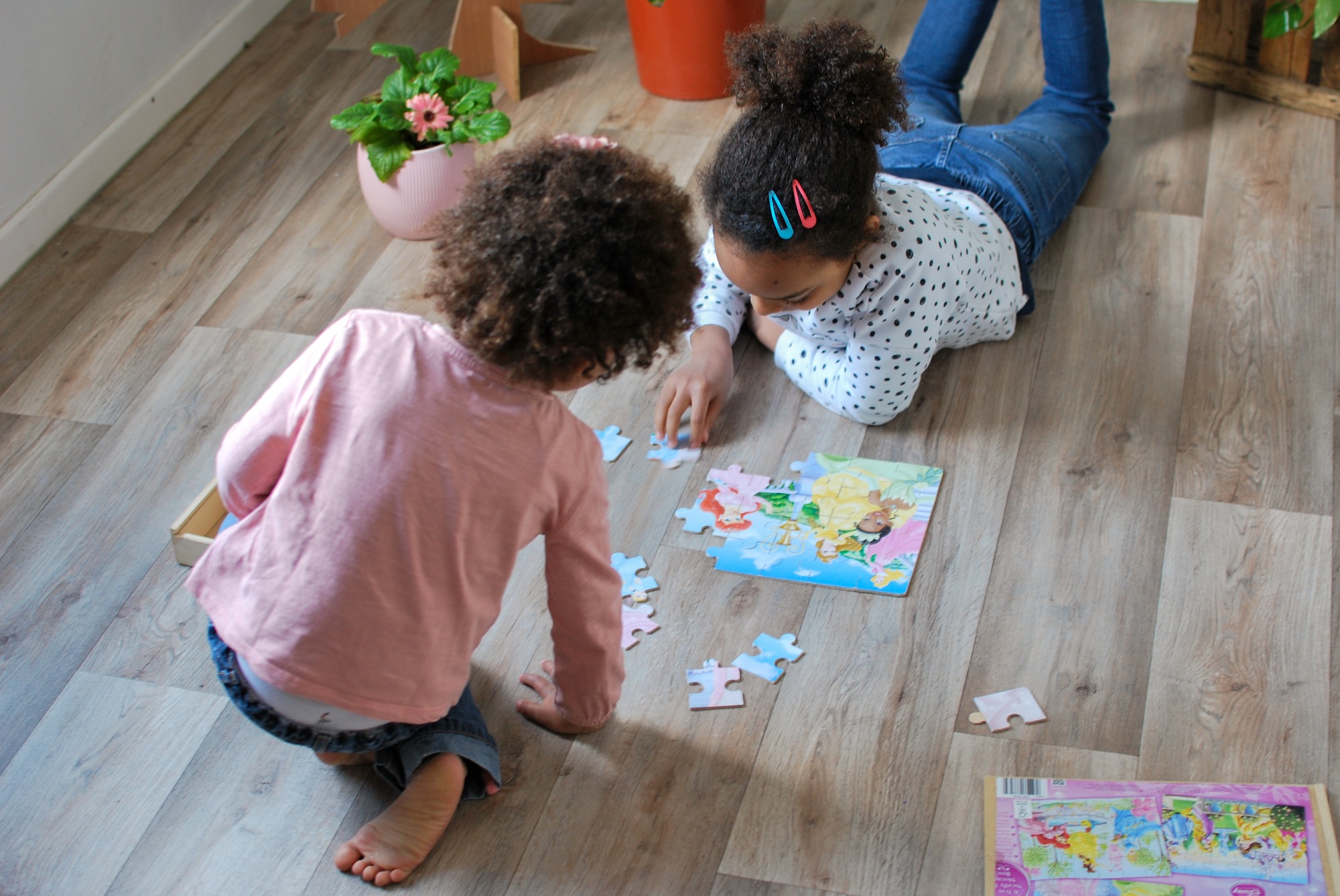 Two young girls of mixed origine making a colorful jigsaw puzzle in their bedroom