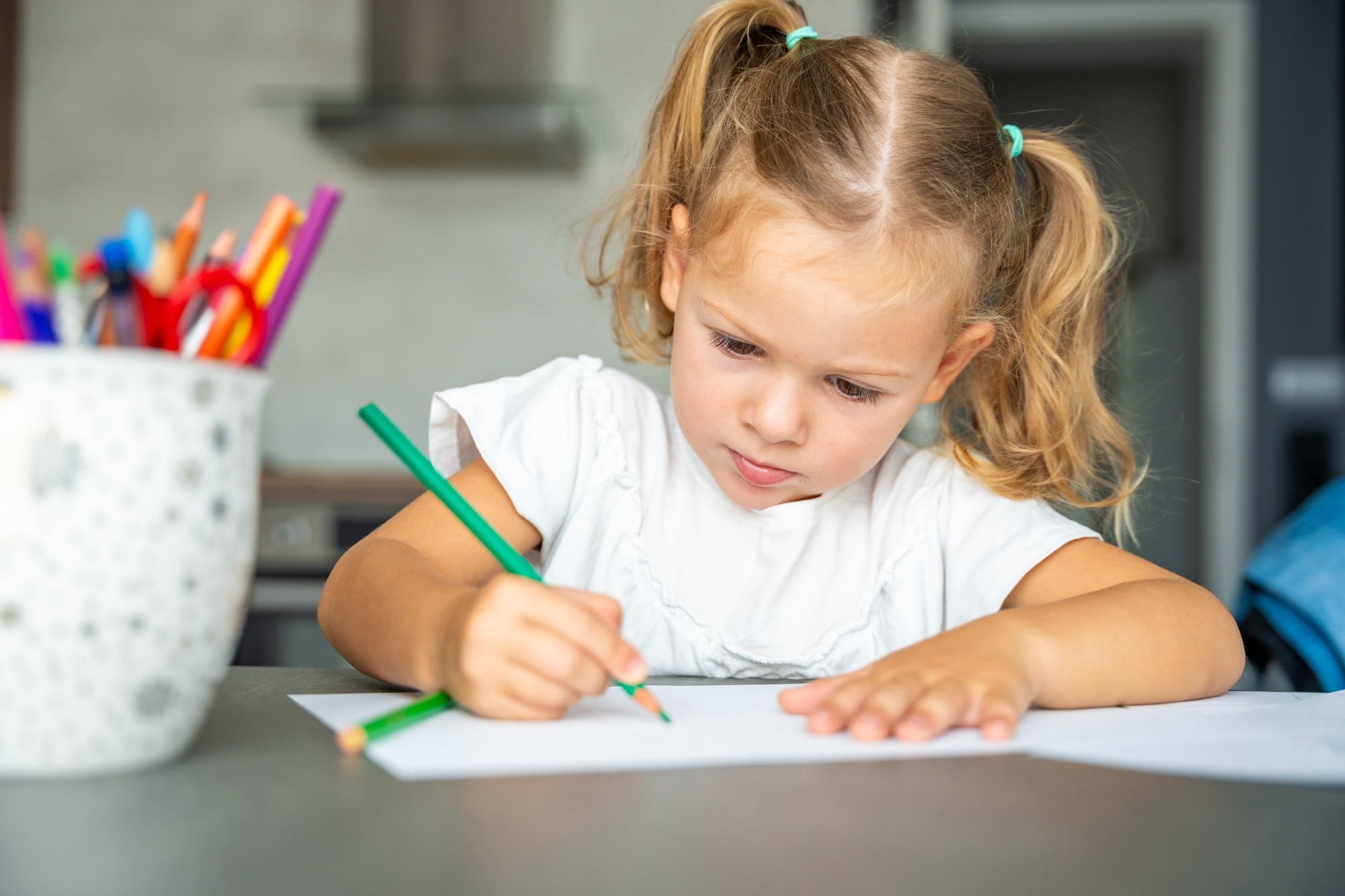 little girl draws with colored pencils in home